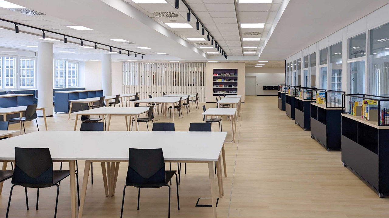 Tische, Stühle und Bücherwagen in einem hellen Raum