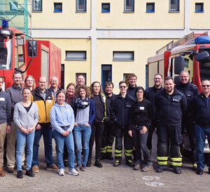 Zwei Feuerwehrwagen, zwischen ihnen steht eine Menschengruppe