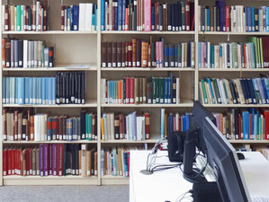 Bücher im Regal und Computer in einer Bibliothek