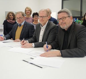 Personen am Tisch unterzeichnen einen Vertrag