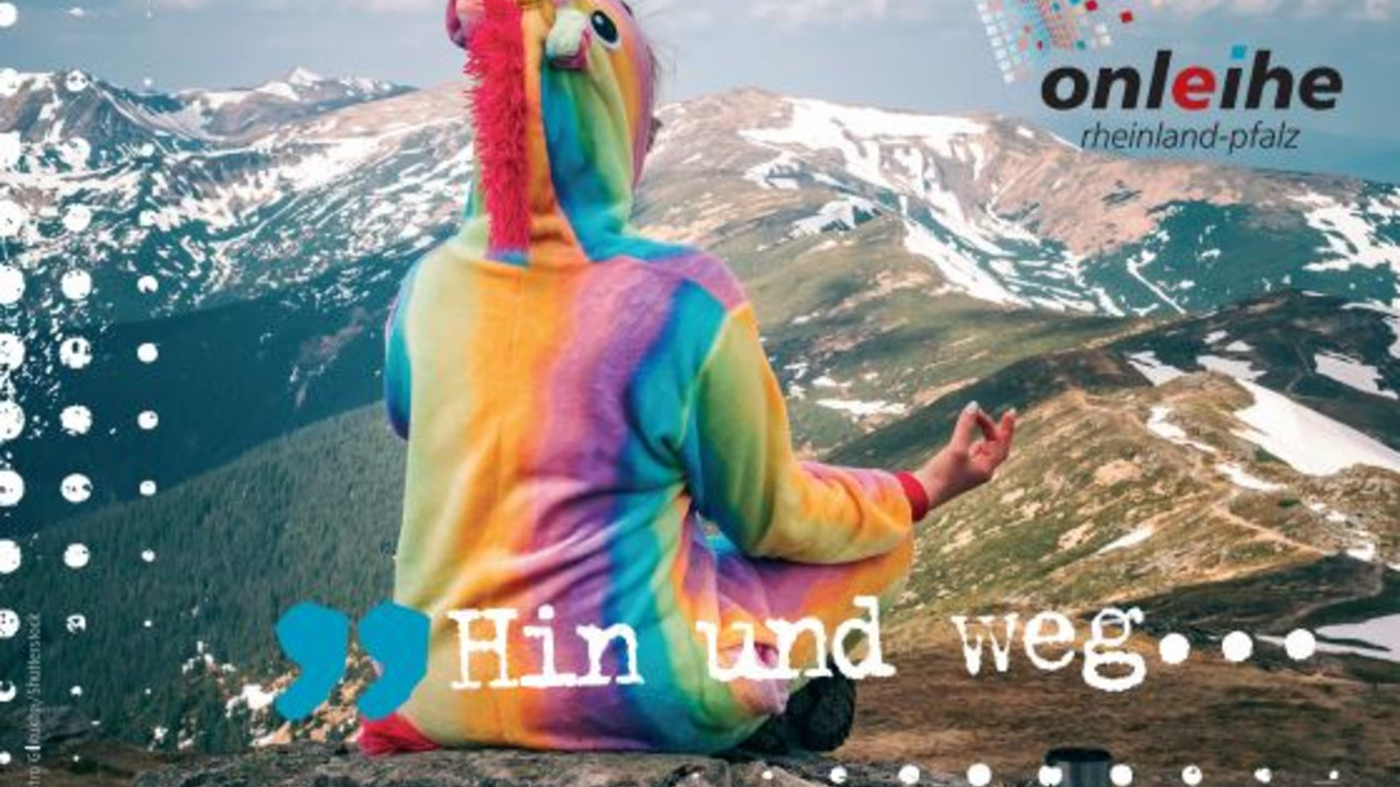Person in Regenbogenkostüm sitzt im Schneidersitz vor Bergpanorama