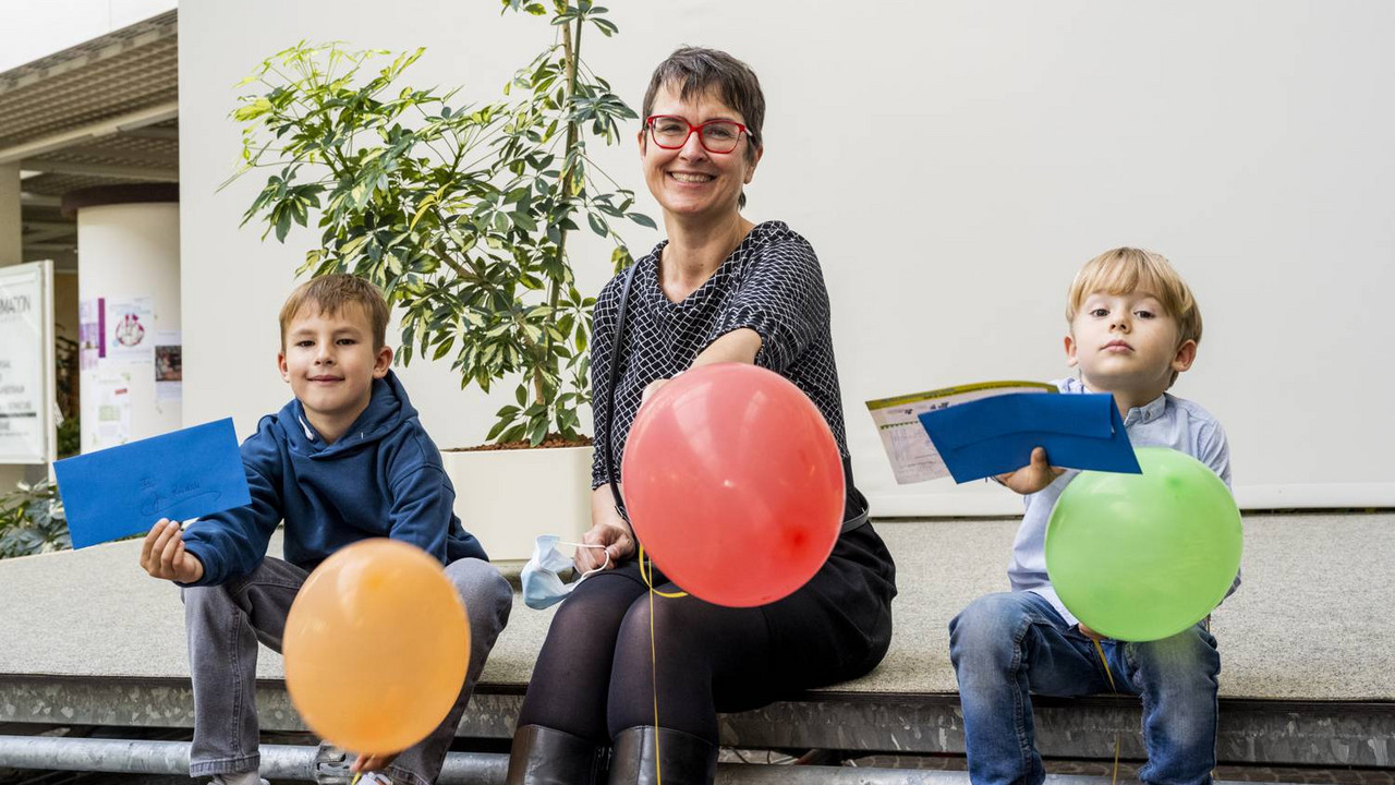 Ute Bahrs sitzt in der Mitte der beiden Gewinnern des Wettbewerbs. All drei halten Luftballons.