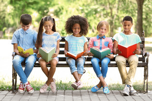 Kinder mit Büchern auf einer Parkbank
