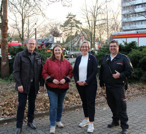 4 Personen vor Feuerwehrautos