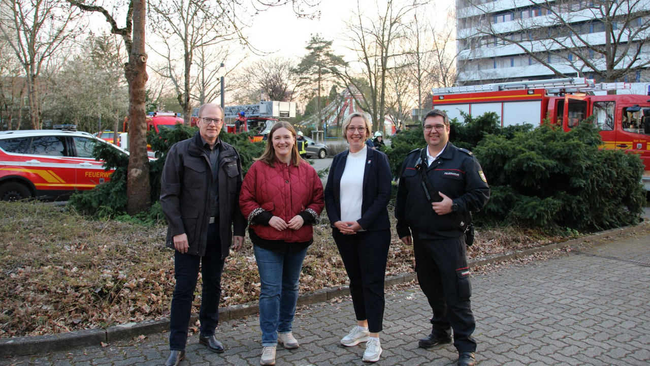 4 Personen vor Feuerwehrautos
