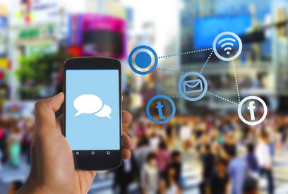 Hand hält Smartphone, auf diesem sind Sprechblasen zu sehen